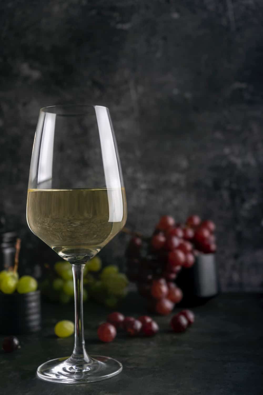 white-wine-in-a-wine-glass-with-red-and-green-grapes-in-the-dark-marble-background