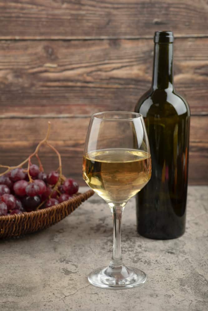 wicker-basket-of-red-grapes-with-glass-of-white-wine-on-marble-table1